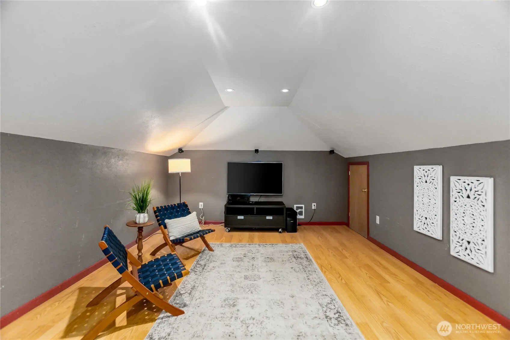 Large upstairs bonus room under a vaulted ceiling, set up as a media room.