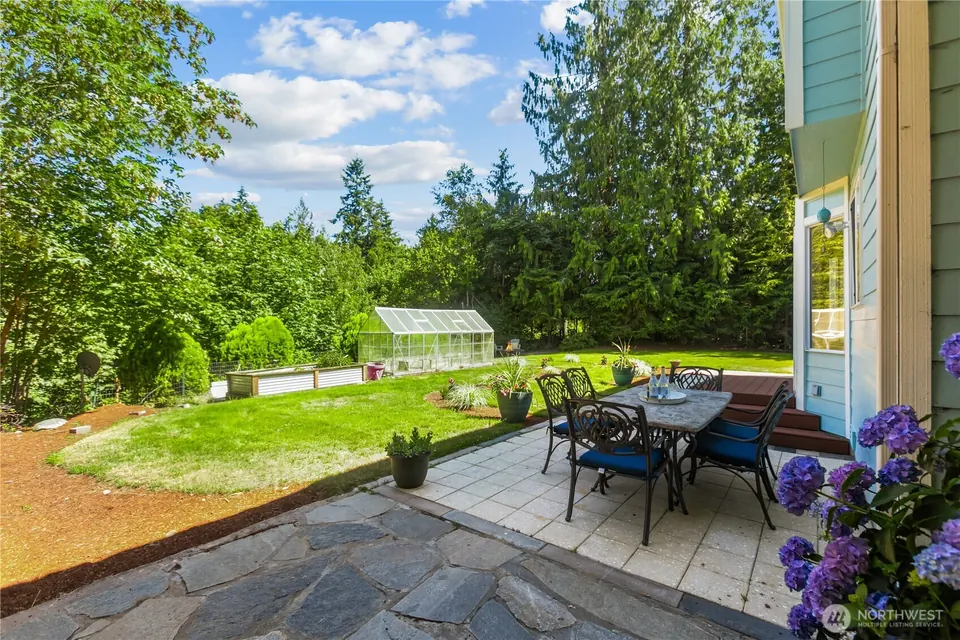 Flagstone patio with an outdoor dining table beside the house and a lawn beyond.